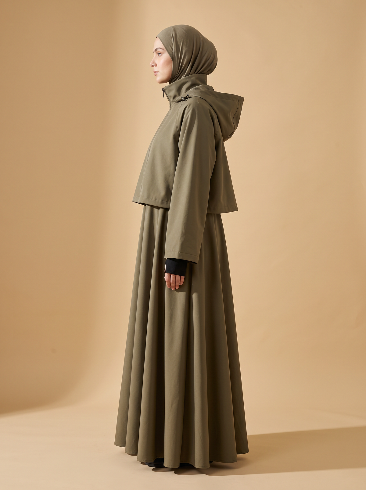 Sakina Zaytoun, veste longue à capuche coloris kaki, vue de profil