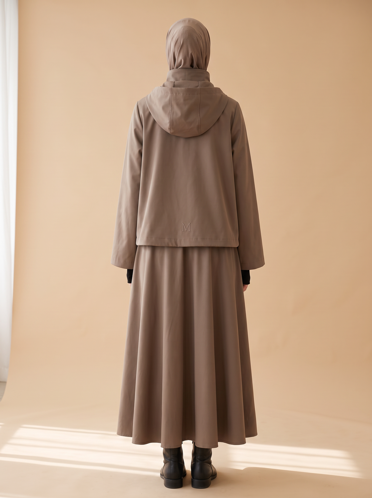 Sakina Tîn, veste longue à capuche coloris taupe, vue de dos, logo M brodé